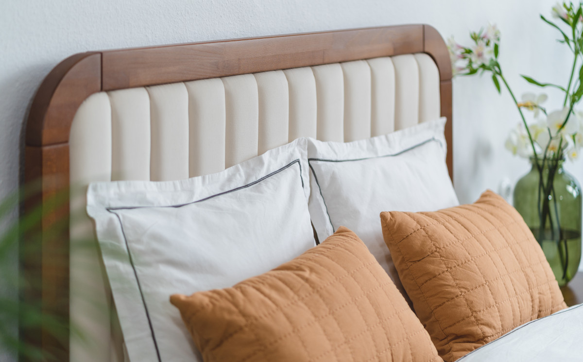 Drewniane łóżko z tapicerowanym zagłówkiem i zaokrąglonych brzegach